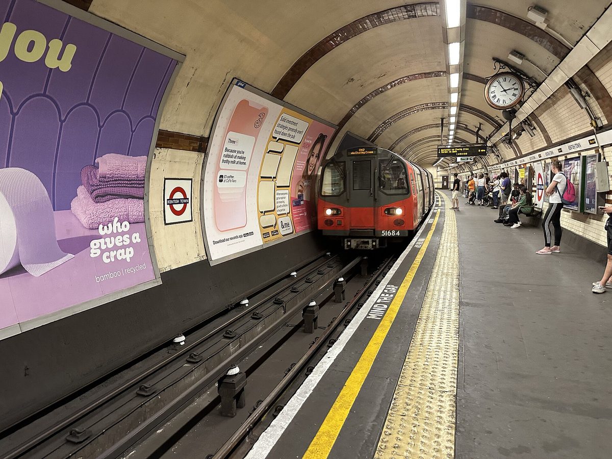 Phone showing one of the best England travel apps next to a London Underground train at the platform