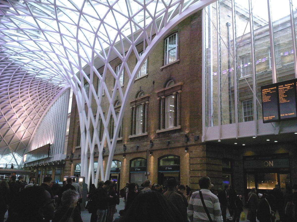 Travellers checking train apps under the departure boards at King's Cross station concourse