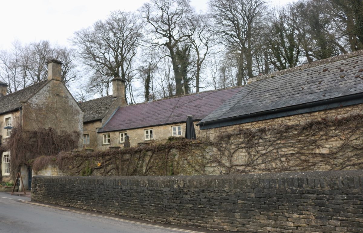 A low-beamed pub interior with a roaring log fire and worn flagstone floor, the classic Cotswold country pub