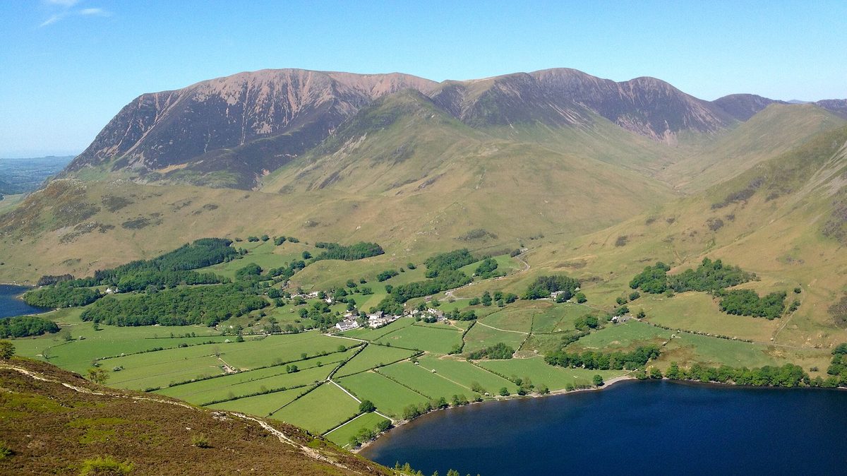 The flat shoreline path along Buttermere with mirror-still water reflecting High Stile and the surrounding fells