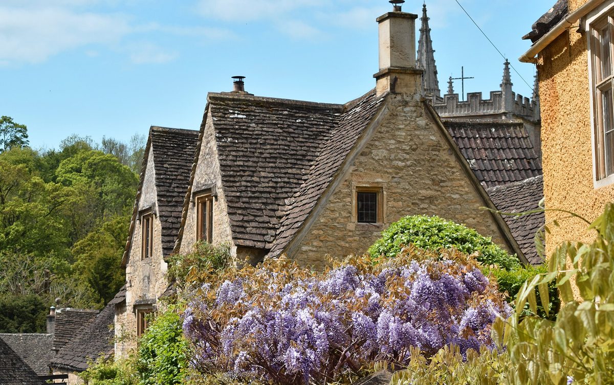 A Cotswolds village scene with stone cottages and a bridge