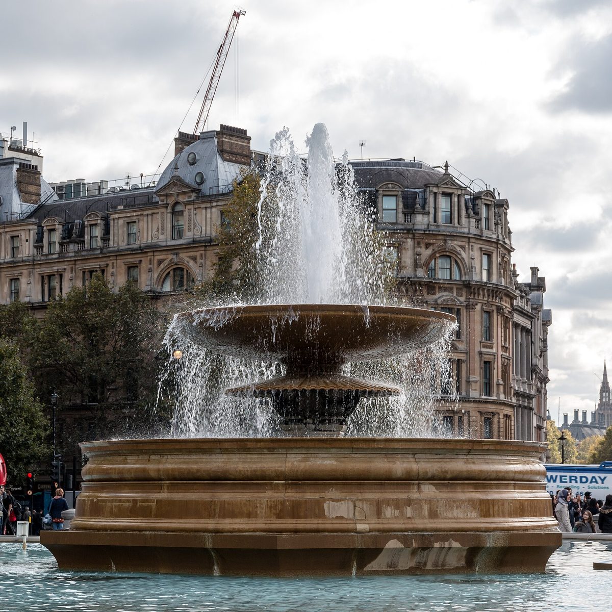 Tourists relaxing by the fountains in Trafalgar Square, London — a reassuring sign that England is safe for tourists exploring the capital.
