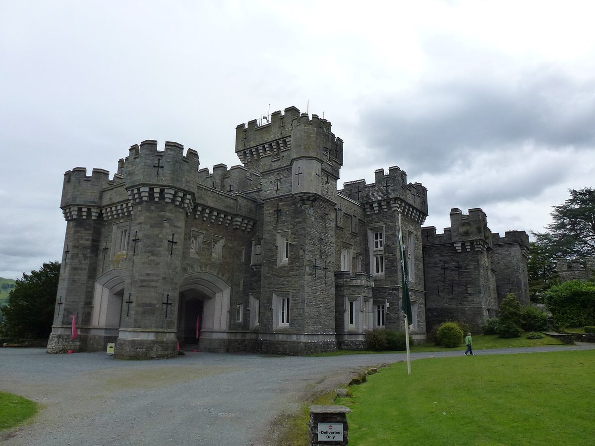 Wray Castle, a Victorian mock-Gothic castle on the wooded western shore of Windermere, framed by dripping trees on a grey day