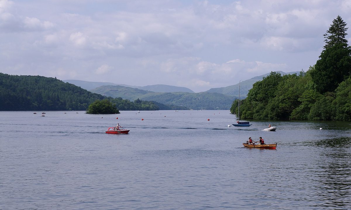 Boats and a stone jetty at Bowness-on-Windermere with crowds strolling the lakeside promenade